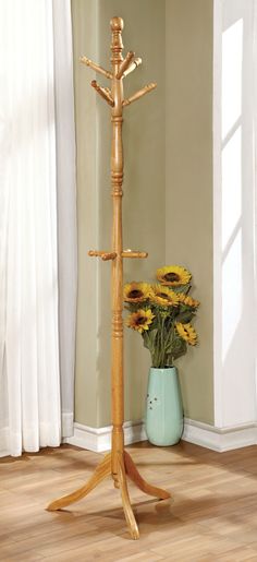 a vase with sunflowers in it next to a wooden coat rack on the floor