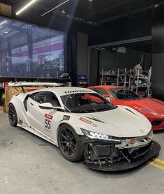 two sports cars parked in a garage next to each other