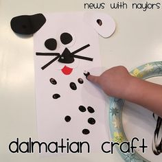 a child's hand is pointing at a paper cat on a plate with black dots