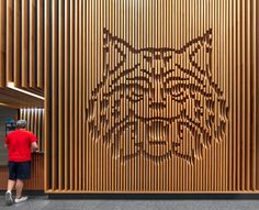 a man standing in front of a wooden wall with a tiger design on it's side