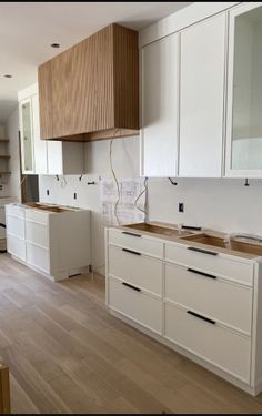 an empty kitchen with white cabinets and wood floors