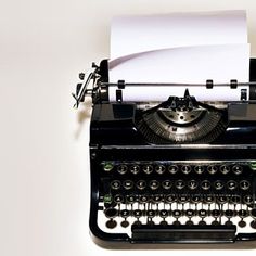 an old fashioned black typewriter with white paper on it's top and bottom