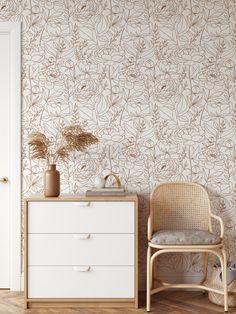 a white dresser sitting next to a wall with flowers on it and a chair in front of it