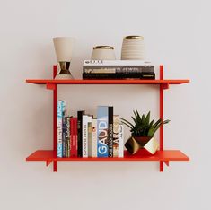 two red shelves with books and plants on them