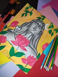 some colored pencils are next to an art project with flowers and a lion on it