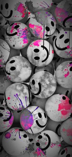 many smiley faces painted in pink and black with paint splattered on the surface