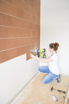 a woman kneeling down on the floor with a drill