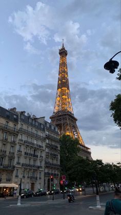 the eiffel tower is lit up at night, with people crossing the street