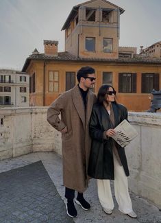 a man and woman standing next to each other in front of a building with a clock tower