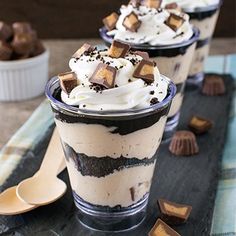 three dessert cups with chocolate and marshmallows in them on a black table