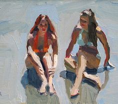 two women sitting on the beach with their legs crossed