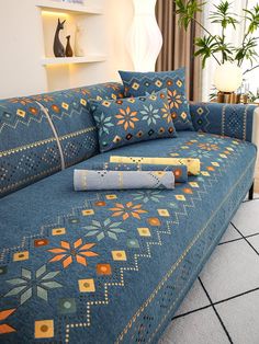 a blue couch with decorative pillows on it in front of a potted plant and bookshelf