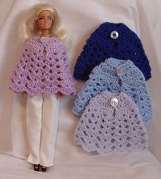 three crocheted doll clothes are displayed on a white sheet with the doll in it