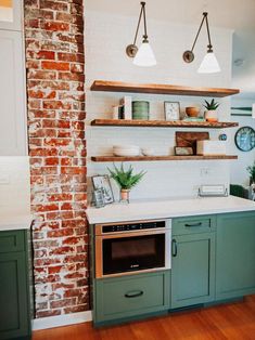 a kitchen with brick walls and green cabinets, white counter tops and open shelving above the stove