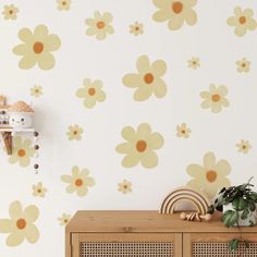 a white wall with yellow flowers on it and a wooden cabinet in the foreground