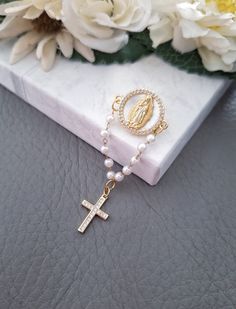 a rosary with a cross on it sitting next to some white flowers and greenery