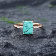 a gold ring with a turquoise stone surrounded by white diamonds on top of a rock