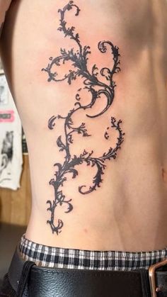 a woman's lower back tattoo with vines on it