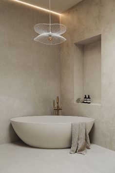 a white bath tub sitting in a bathroom next to a sink and mirror with lights above it