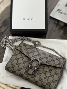 This Gucci Dionysus GG Supreme Chain Wallet Clutch is a stylish and functional accessory for women. The bag features a snap closure and a chain strap for easy carrying. The exterior is made of canvas and leather, with a beige GG pattern that is both classy and elegant. The bag has a small size of 8x5x2.3 inches, making it perfect for a night out or a casual day. The interior is lined with beige cloth and there are two compartments inside to store your essentials. The bag comes with an original box and dust bag and is in excellent condition. Functional Accessories, Wallet Chain, Gucci Dionysus, Clutch Wallet, Chain Strap, Bags Handbags, Dust Bag, Bag Lady, Shoe Accessories