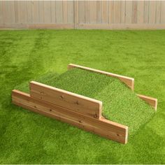 a wooden bench sitting on top of green grass covered ground in front of a fence