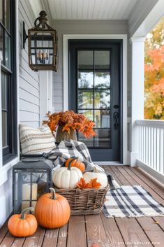 pumpkins and gourds are sitting on the front porch with an lantern in the background