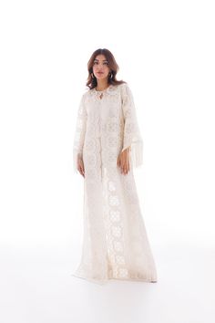 This long ivory coat is cut from sheer organza and is detailed with playful fringes on the sleeves. Pair it with a crepe slip and rawsilk bootcut pants for a chic and elegant look. Elegant Long-sleeved Dress With Tassels, Elegant Long Sleeve Dress With Tassels, Elegant Kaftan With Bell Sleeves, Chic Long Kaftan For Party, Elegant Beige Fringe Dress, Elegant Long Cream Abaya, Elegant White Party Abaya, Elegant Long Sleeve Kaftan With Tassels, Elegant Long Cream Kaftan