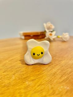 an egg shell with a smiley face is sitting on a table next to some flowers