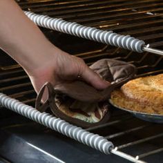 someone is removing a pie from the oven with tongs and an oven mitt