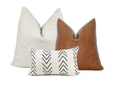 three pillows with different patterns on them, one is brown and the other is white