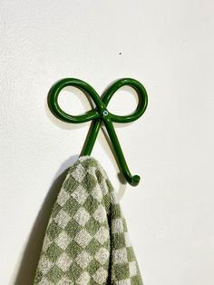 a pair of green scissors hanging on the wall next to a white towel with checkered pattern