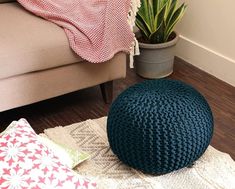 a blue crocheted pouff sitting on top of a wooden floor next to a potted plant