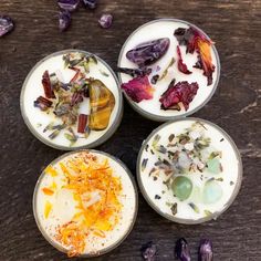 four bowls filled with different types of food on top of a wooden table next to dried flowers