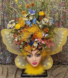 a woman's head with flowers on top of it and yellow feathers around the head