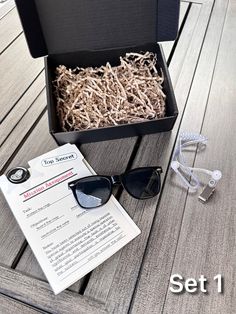 an open box with sunglasses and some wood shavings on the ground next to it