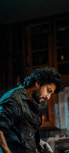 a man is working on something in a kitchen with dark lighting from the window behind him