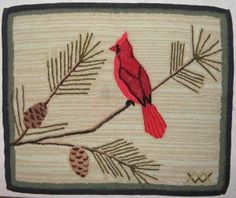 a red bird sitting on top of a tree branch with pine cones and needles in front of it