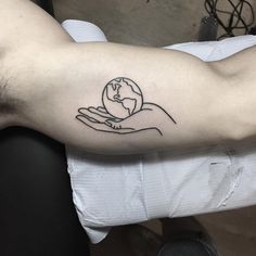 a person with a tattoo on their arm holding a small globe in his hand,