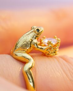 a gold frog ring sitting on top of someone's finger