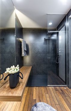 a modern bathroom with wood flooring and black walls, along with a large shower