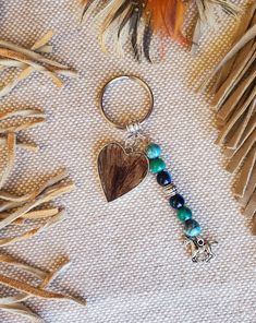 a keychain with a heart on it sitting next to feathers and other items