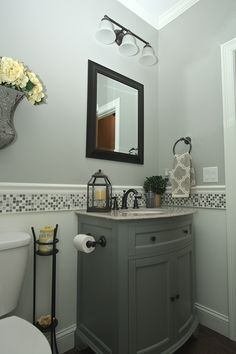 a white toilet sitting next to a sink in a bathroom under a mirror and lights