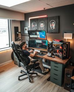 a man sitting at a desk in front of a computer monitor and sound mixing equipment