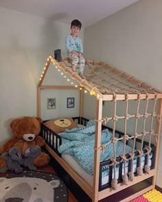 a little boy standing on top of a bunk bed with a teddy bear next to it