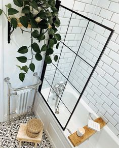 a bathroom with a plant in the corner and a towel rack on the floor next to it