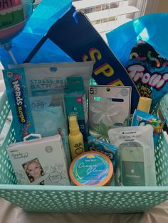 a blue basket filled with baby items on top of a white sheet covered table next to a window