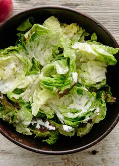 a bowl filled with lettuce on top of a wooden table