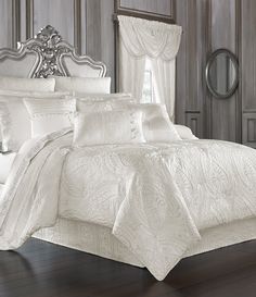 a bed with white sheets and pillows on top of it in front of a mirror