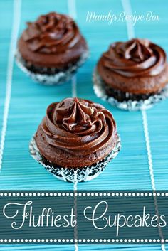 three chocolate cupcakes sitting on top of a blue table with the words fluffyest cupcakes