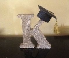 the letter k is made out of glitter and has a graduation cap on top of it